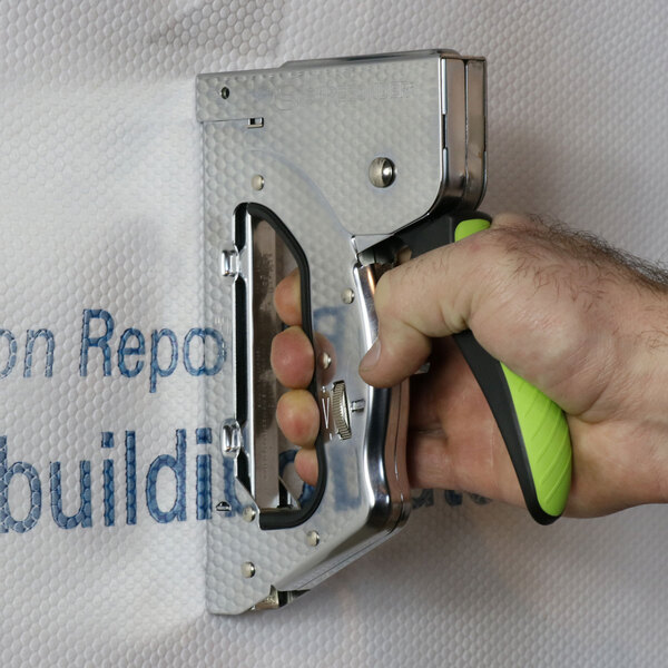A hand uses a Surebonder 3-in-1 steel heavy-duty staple gun with a green and black handle.