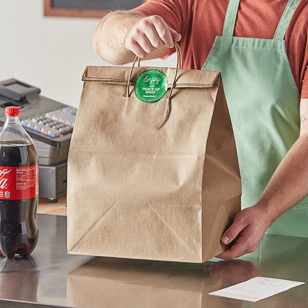 A man in an apron holding a Duro brown paper shopping bag with handles.