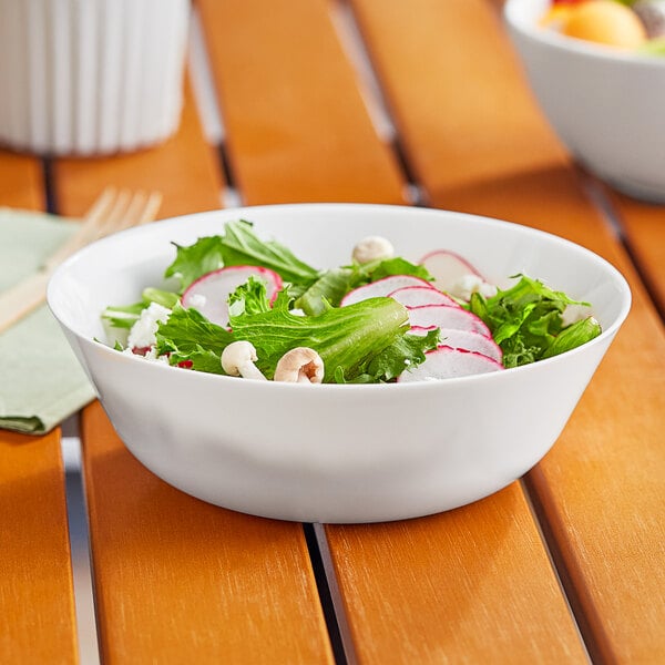 A close up of a World Centric white PLA bowl filled with salad including radishes and nuts.