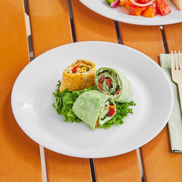 A World Centric reusable white plastic plate with a wrap and salad on it.