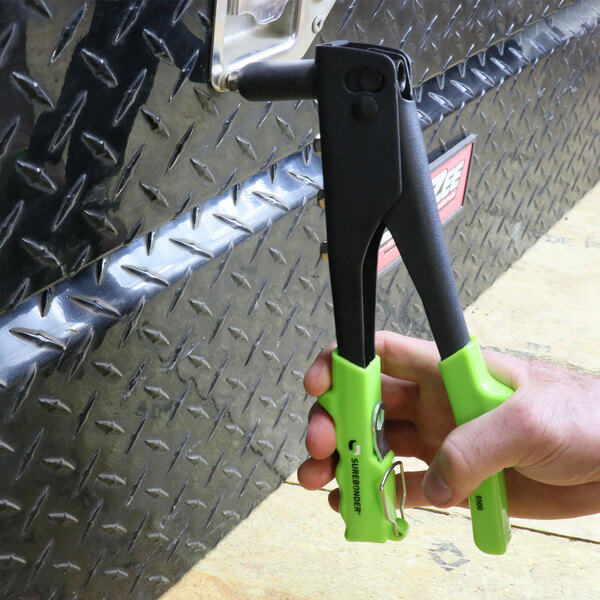A hand using a green Surebonder Heavy-Duty Rivet Tool.