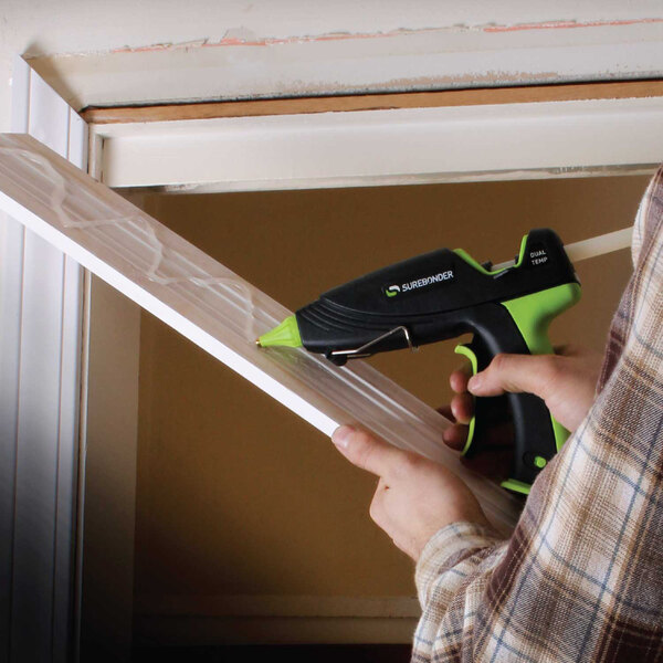 A person using a Surebonder Ultra hot glue gun to attach a window.