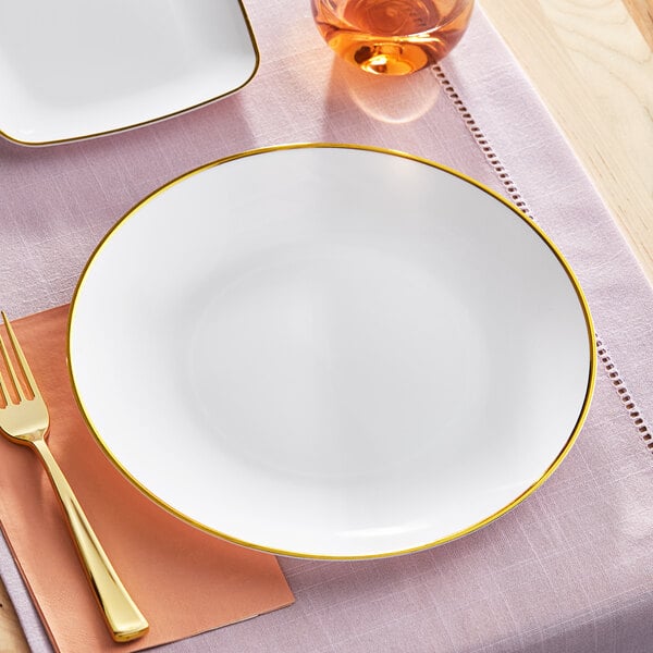 A Visions white plastic plate with gold rim on a table with a fork.
