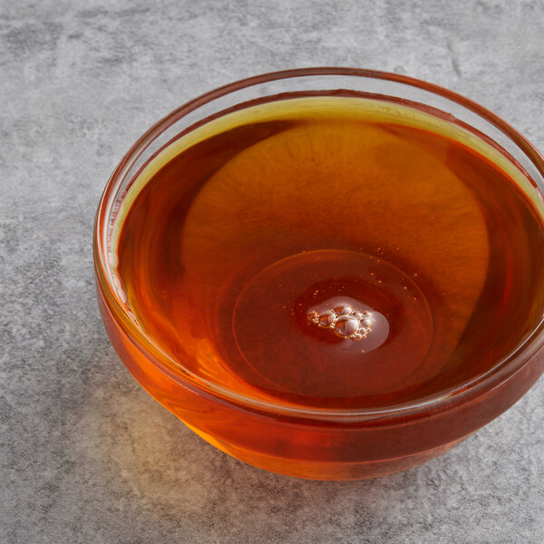 A bowl of Malt Products Nuvert Organic Medium Invert Syrup on a table with a spoon.