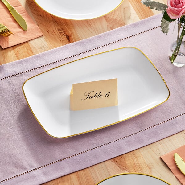 A Visions white plastic rectangular coupe platter with a gold band and a place card on it.