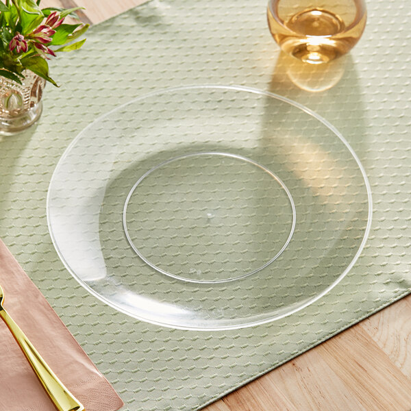 A clear Visions plastic coupe plate with a fork and knife on it on a table