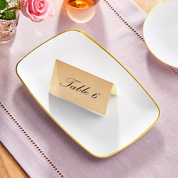 A Visions white rectangular plastic coupe platter with a gold place card on it.