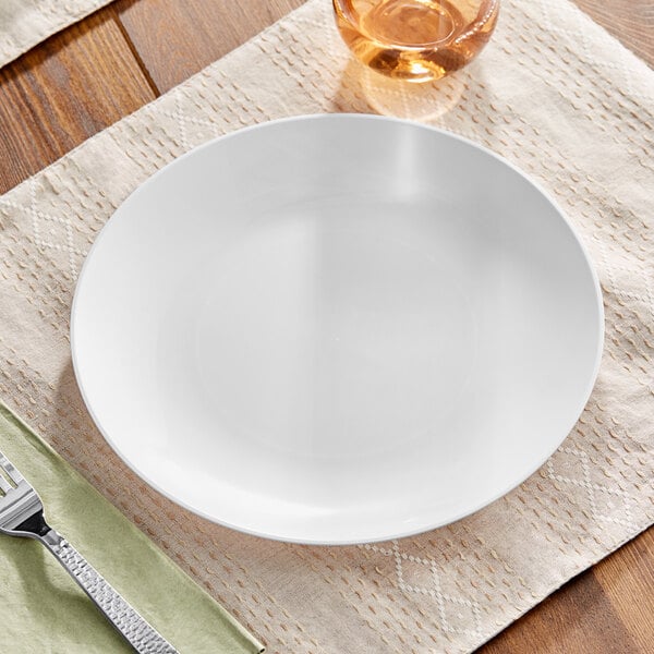 A white Visions plastic coupe plate on a table with a fork.