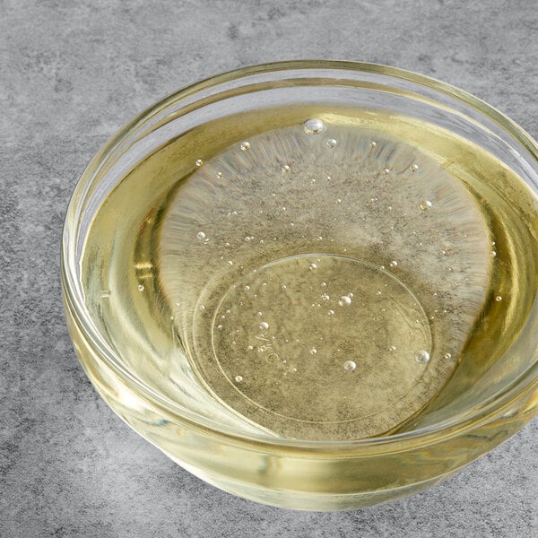 A clear bowl of yellow RiceRite rice syrup with bubbles in it.