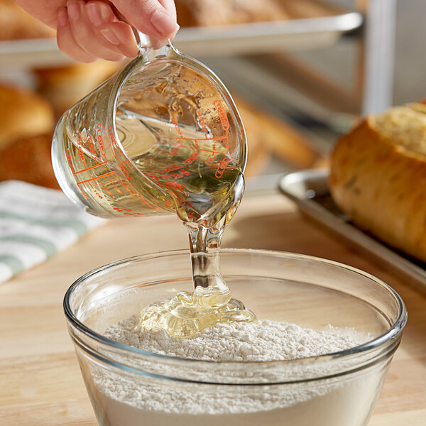 A person pouring Malt Products RiceRite Rice Syrup into a measuring cup