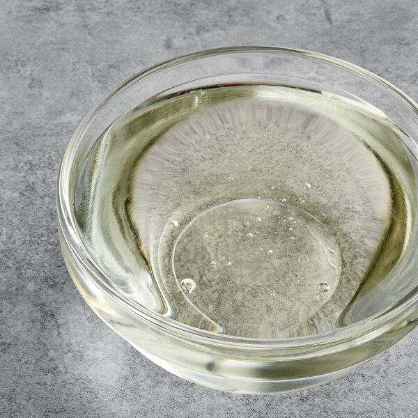 A clear glass bowl with clear liquid in it with a spoon in the liquid.