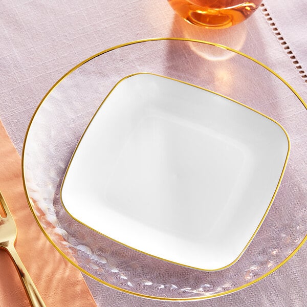 A white square plastic plate with a gold rim on a table.