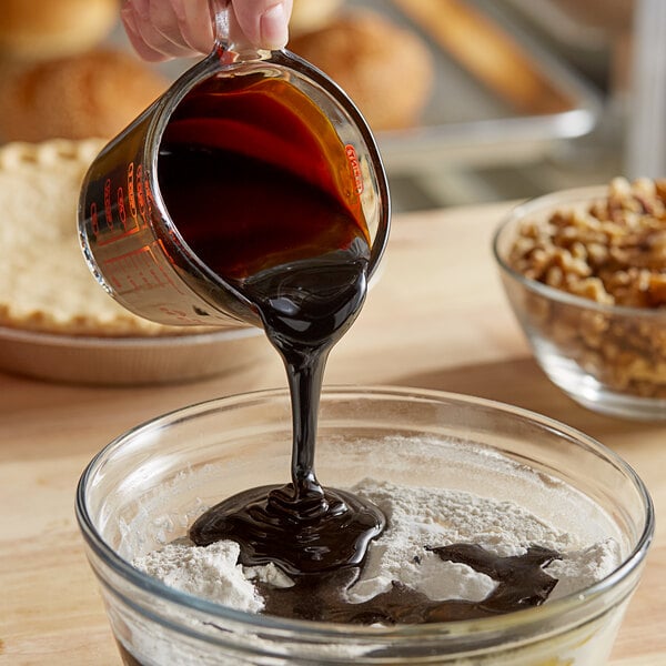 A person pouring Malt Products CaneRite Blackstrap Molasses into a bowl of flour.