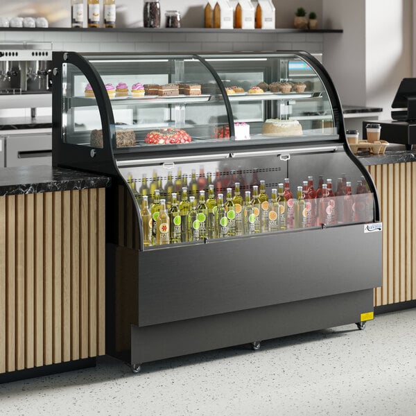 An Avantco black curved dual service refrigerated air curtain merchandiser with drinks and pastries on shelves.