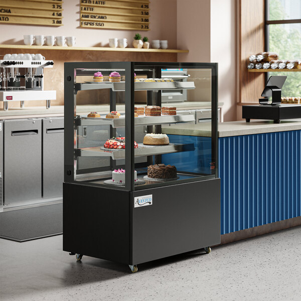 A black Avantco refrigerated bakery display case with cakes inside.