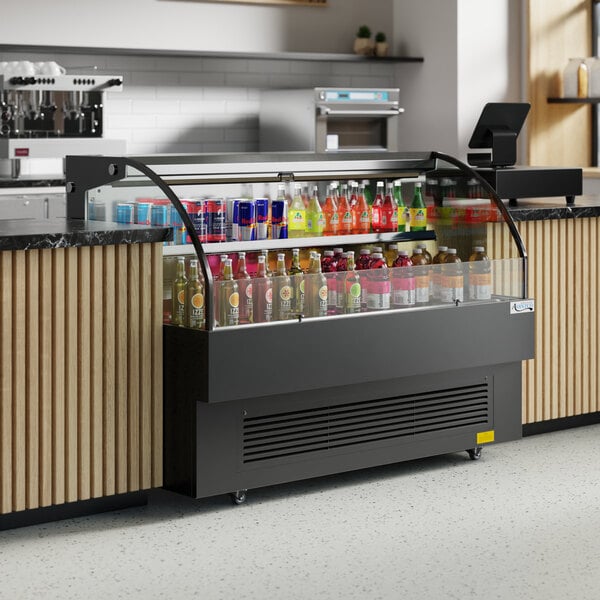 An Avantco black horizontal air curtain merchandiser on a counter with drinks and snacks in it.