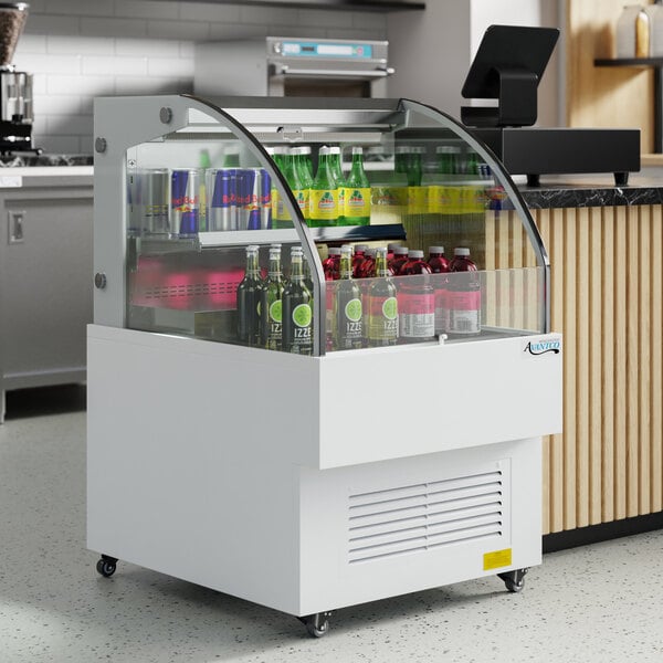 An Avantco white horizontal air curtain beverage cooler with bottles in it.