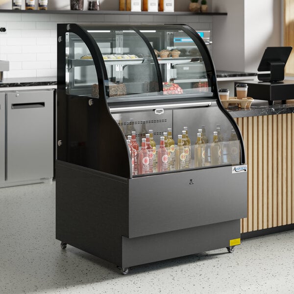 An Avantco black refrigerated display case with a curved glass door and dual service shelves holding drinks.