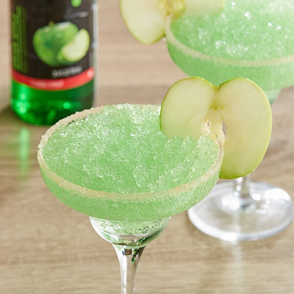 A green drink in a glass with DaVinci Gourmet Classic Green Apple Flavoring and a slice of green apple.