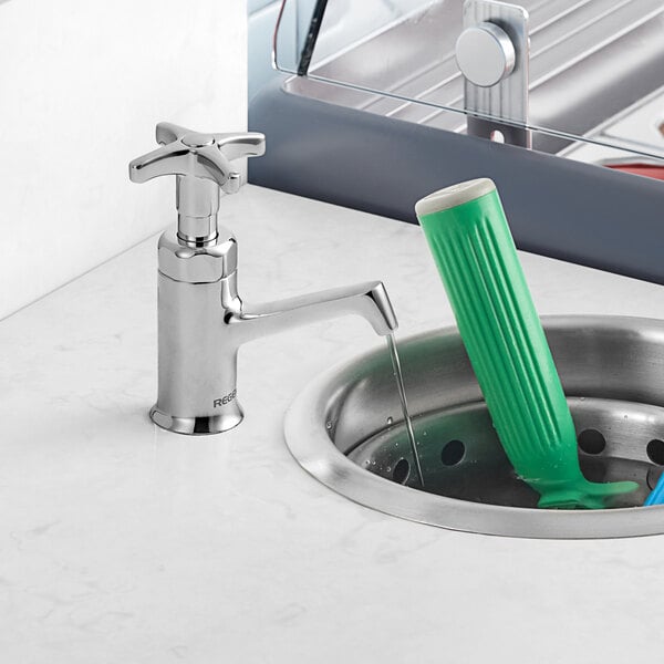 A Regency dipper well faucet in a sink with a green object.