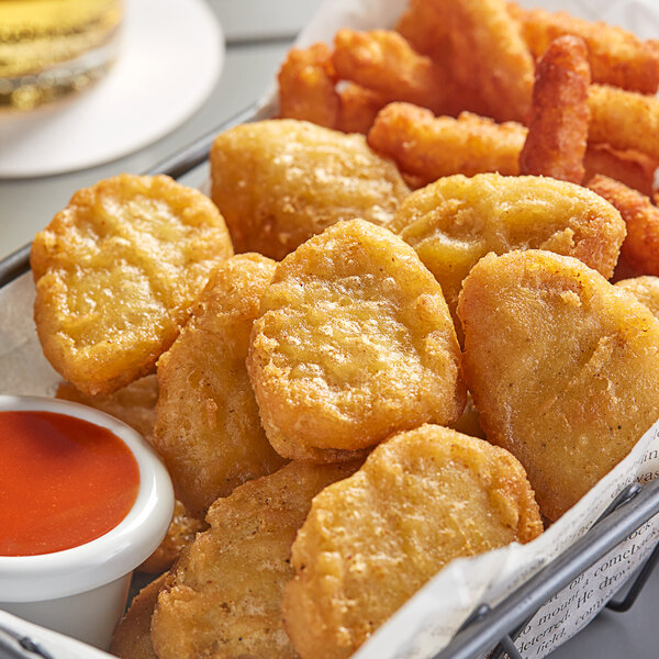 A basket of Beyond Meat plant-based vegan chicken nuggets with dipping sauce on a table.