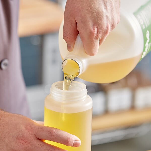 A hand pouring Zero Acre Sugarcane Oil into a jug.