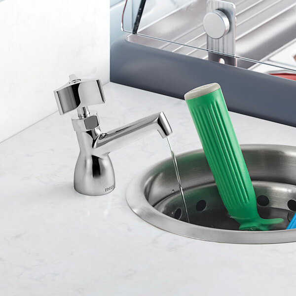 A Regency dipper well faucet with a green handle in a sink.