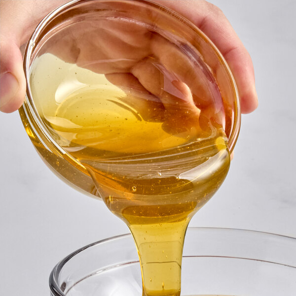 A bowl of golden honey being poured into another container.