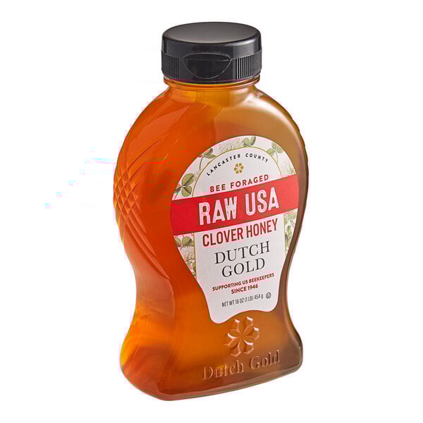 A bottle of Dutch Gold Raw Clover Honey with a white label on a table.
