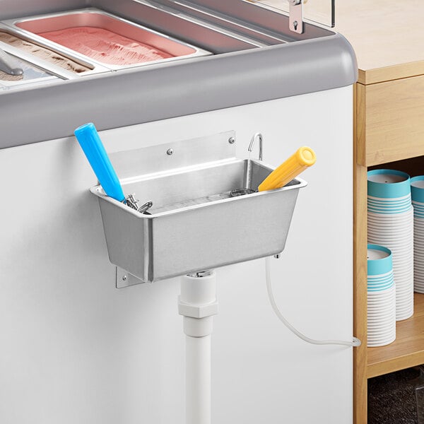 A metal container with a yellow handle in it above a sink.