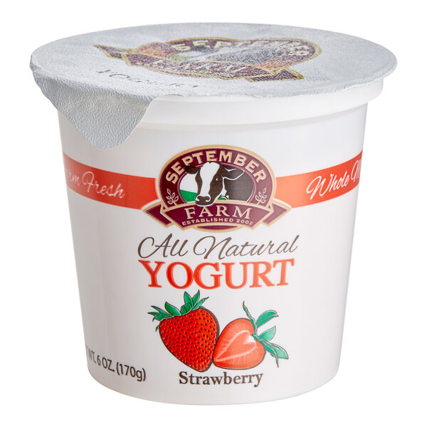 A white September Farm strawberry yogurt container with a lid and a red and white label, with a strawberry on top.