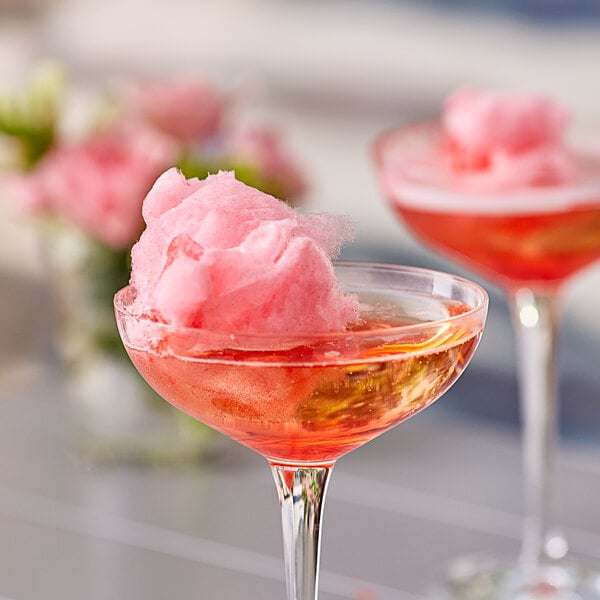 A pair of martini glasses with pink cotton candy floss sugar in them.