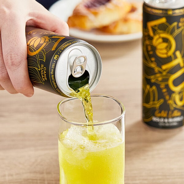 A hand pouring Lotus Plant Power Energy Drink into a glass of yellow liquid.