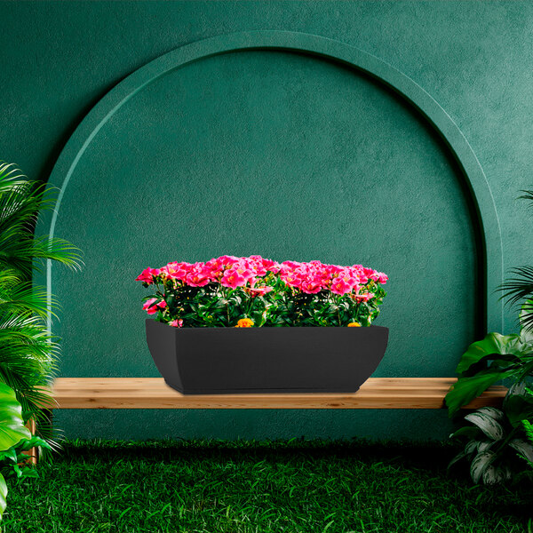 A Floridis Amsterdam rectangular black planter with pink flowers on a wooden bench.