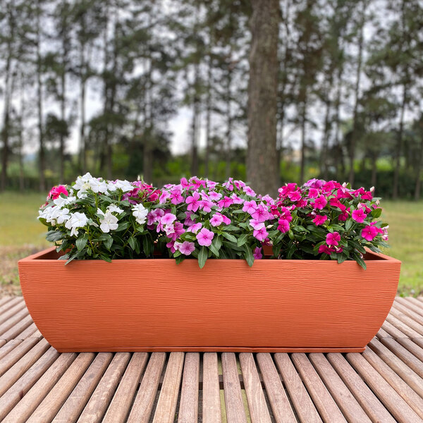 A Floridis rectangular terra cotta planter with flowers on a wooden surface.