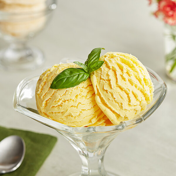 A bowl of yellow Lloyd's of Pennsylvania mango ice cream with a green leaf on top.