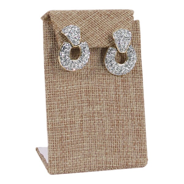 A pair of diamond earrings on a burlap linen display stand.