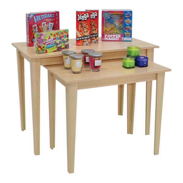 A 2-piece maple laminate wood nesting display table set with different items on it.
