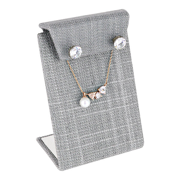 A gray linen earring and necklace display stand with a necklace and earrings displayed.