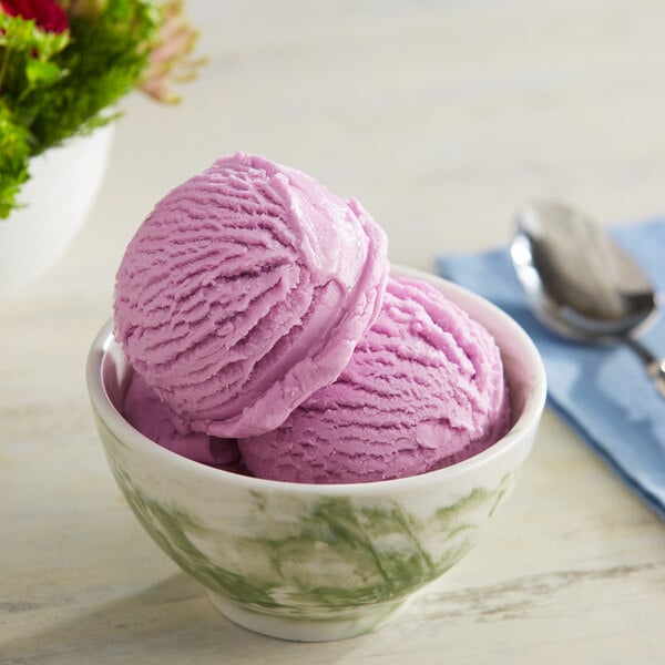 A bowl of pink ice cream topped with Lloyd's of Pennsylvania Black Cherry flavoring with a spoon.