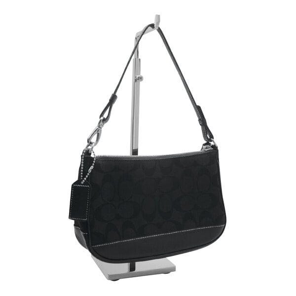 A black Coach purse on a chrome-plated countertop display rack.