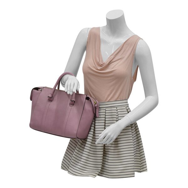 A glossy white plastic female mannequin wearing a pink shirt and striped skirt holding a pink bag.