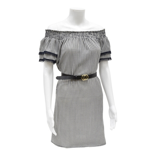 A glossy white plastic female 3/4 body torso mannequin with removable arms, dressed in a checkered off-shoulder dress and a black belt.