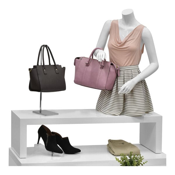 A mannequin display with a black purse and shoes on a white Glossy White Melamine Riser.