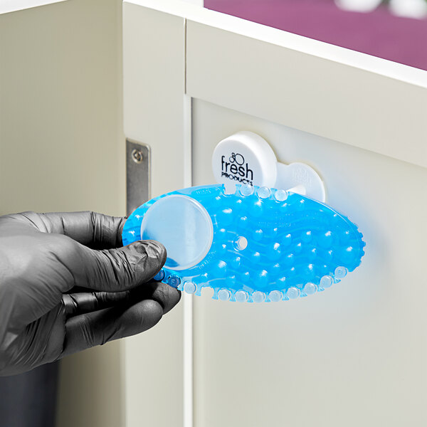 A hand in black gloves holding a blue Fresh Products Curve air freshener.