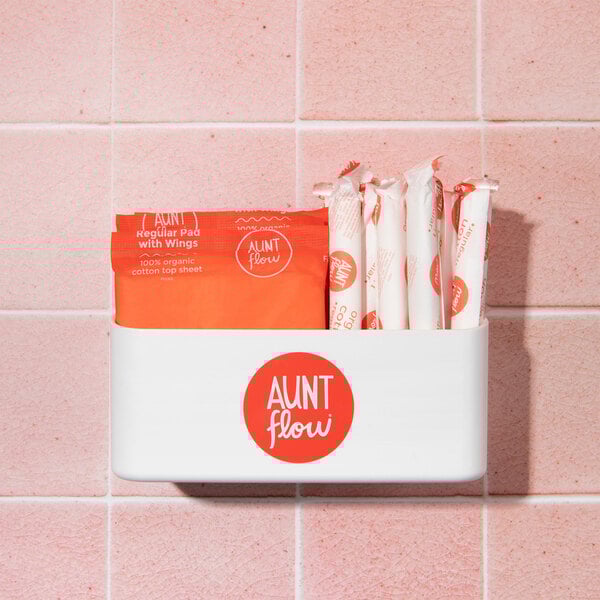 A white Aunt Flow dispenser box with red and white packages inside, with a red circle and white text on the package.