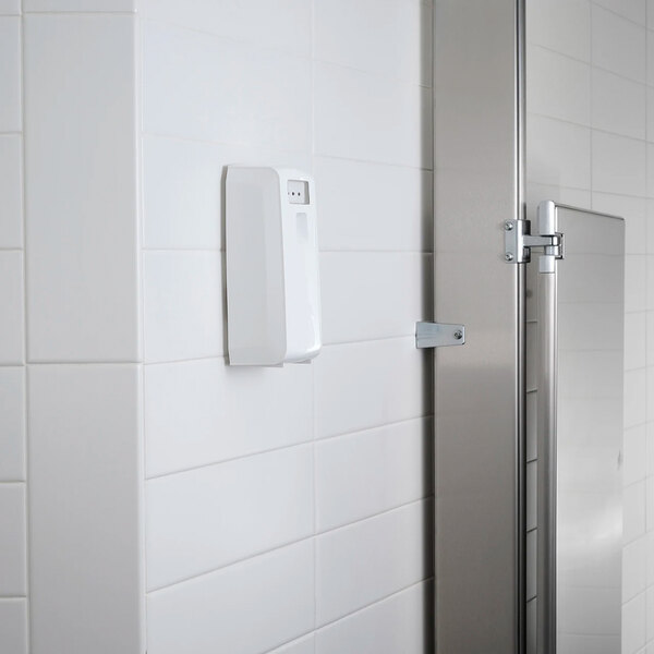 A white metered aerosol air freshener cabinet mounted on a tiled wall.