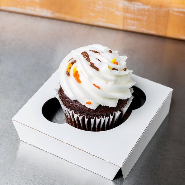 A Baker's Lane cupcake insert holding a cupcake with white frosting and sprinkles in a white box.