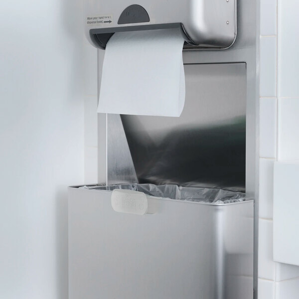 A stainless steel paper towel dispenser and waste bin mounted on a wall in a restroom.