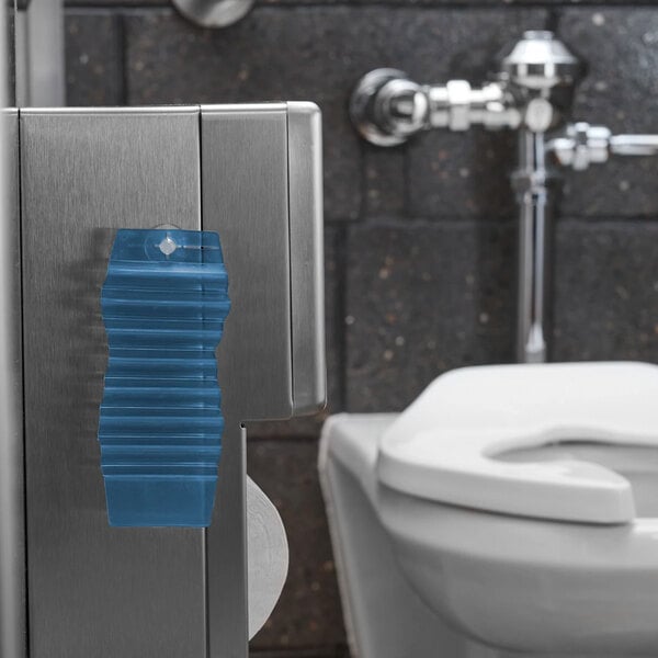 A blue passive air freshener hang tag attached to a metal surface in a restroom.